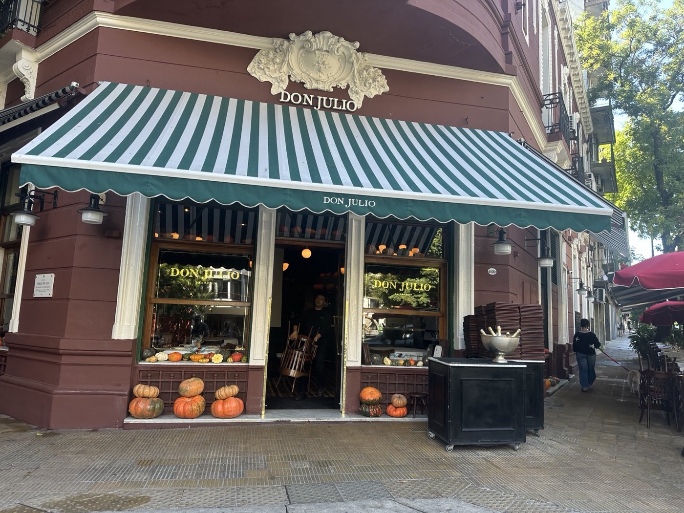 Facade of Don Julio restaurant in Buenos Aires, with a deep green and white striped awning and an ornate cream-colored crest.