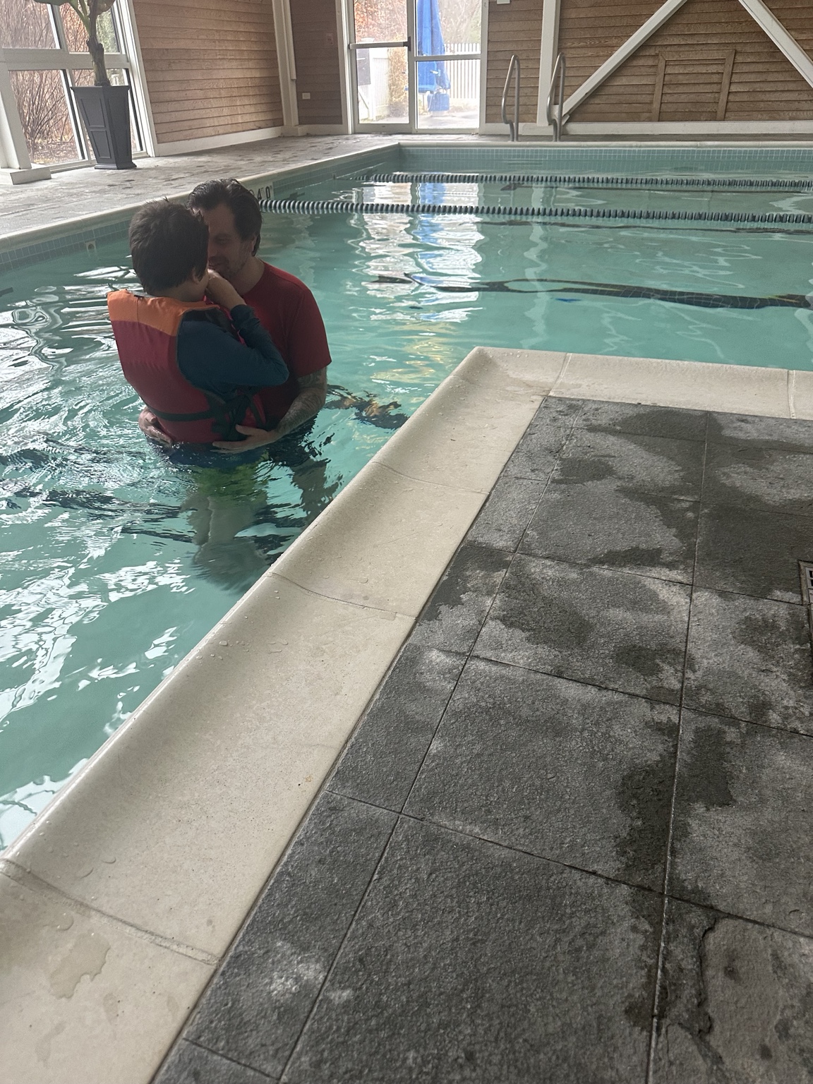 James and his dad together in the water, with his dad holding him close.