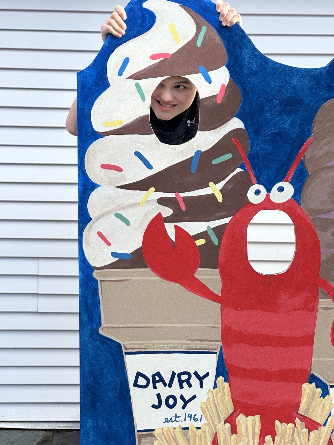 James peeking through Dairy Joy’s painted ice-cream cutout beside a red lobster.