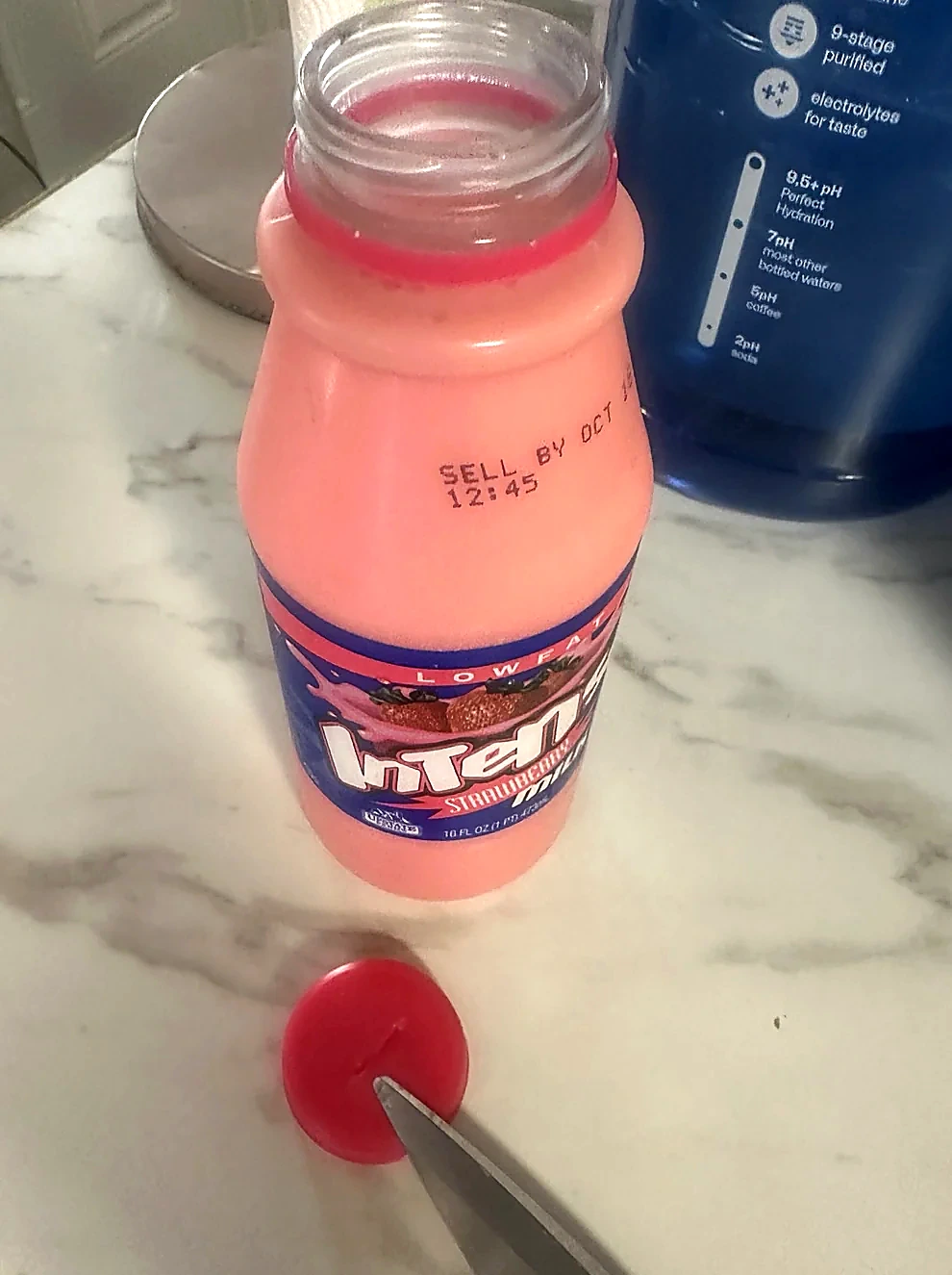 Original photograph of the opened INTENSE strawberry milk bottle beside the removed red cap on the kitchen counter.