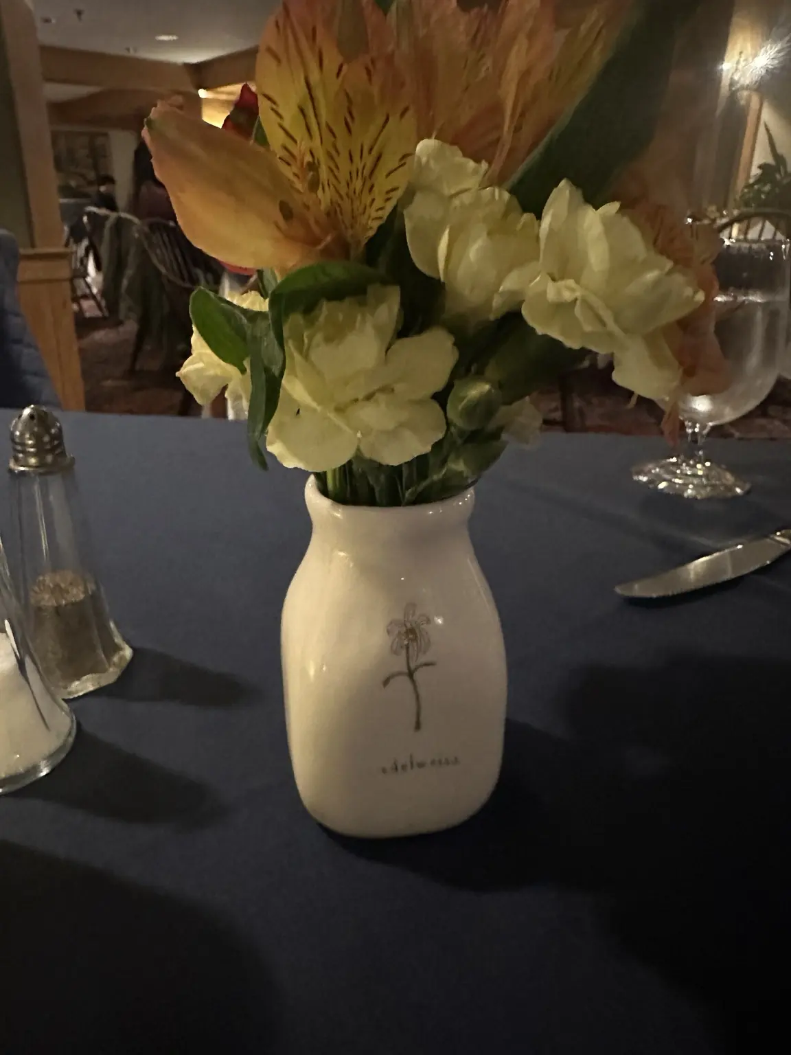 A small mixed flower arrangement in a cream vase on a dark dining table during a von Trapp visit.
