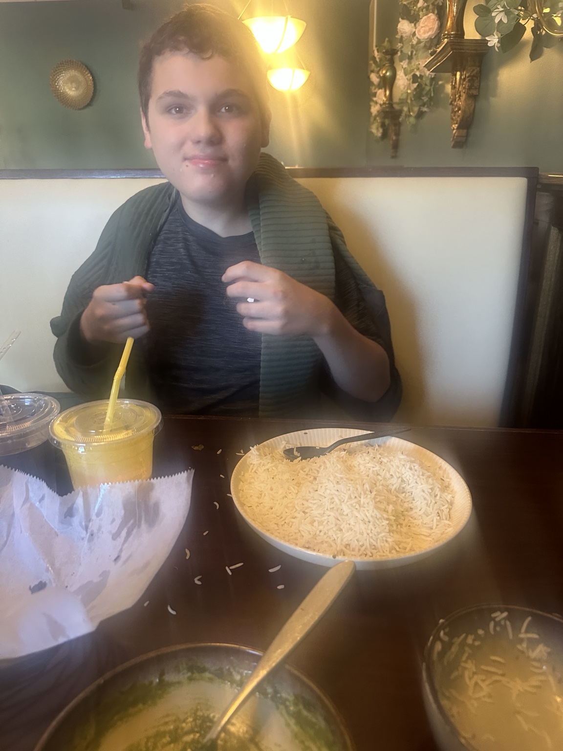 James seated in a booth at Kohinoor, with rice and a mango lassi on the table.