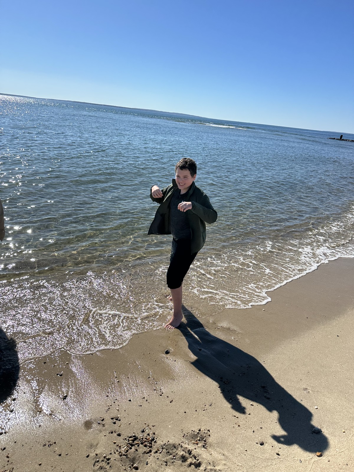 James lifts his arms as he moves along the sunlit waterline.