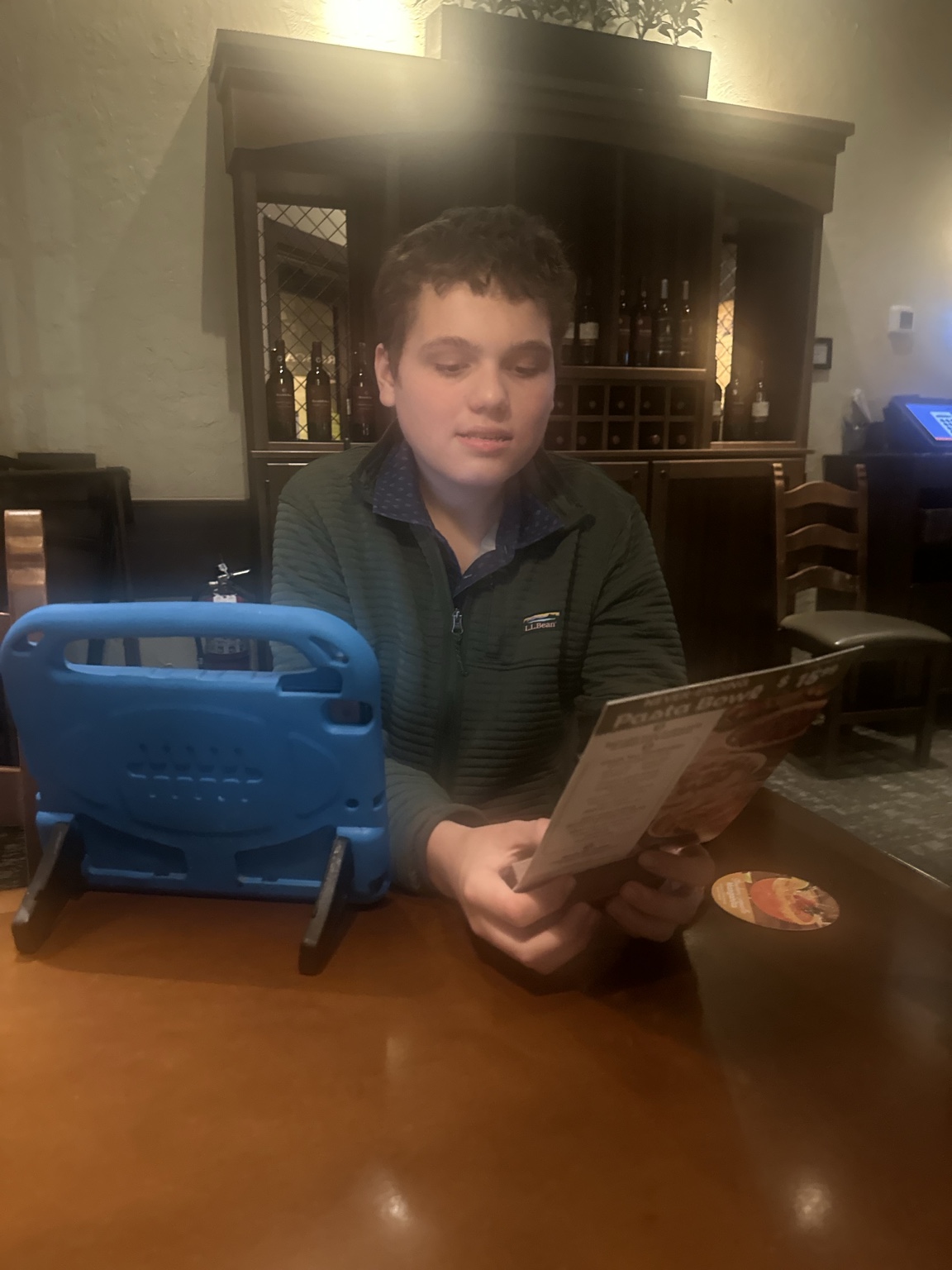 James looks at the pasta menu with his blue AAC device beside him.