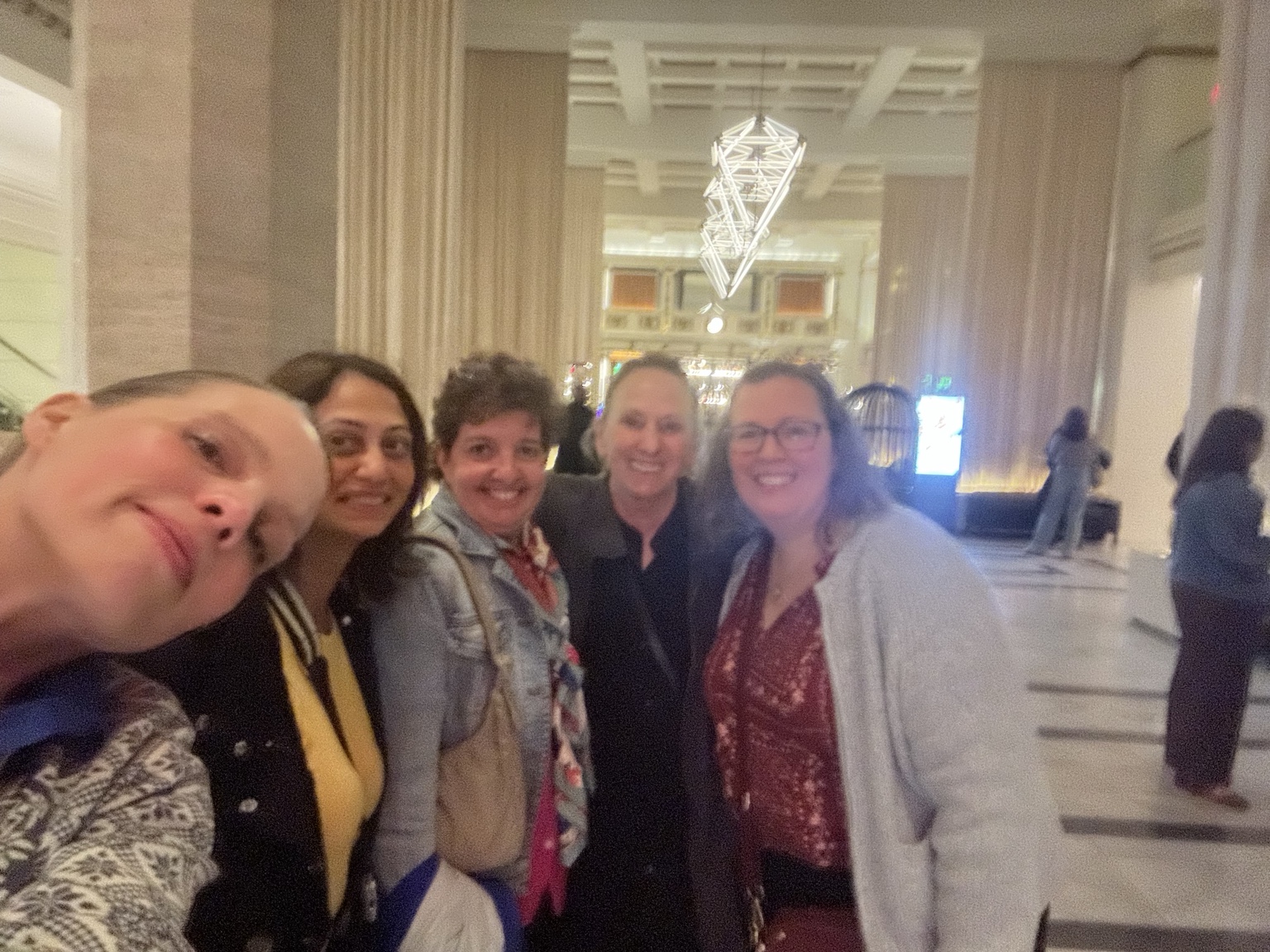 Five people smiling together for a group photograph in the hotel lobby during the summit.
