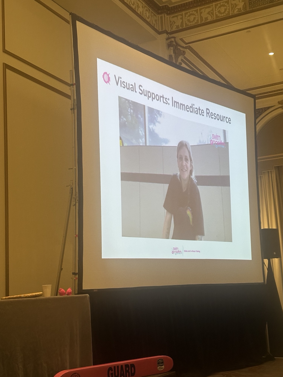 A presentation screen showing a swimming instructor in a video about visual supports.