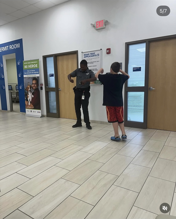 James faces the guard with his arms raised as the guard moves his hands near his waist.