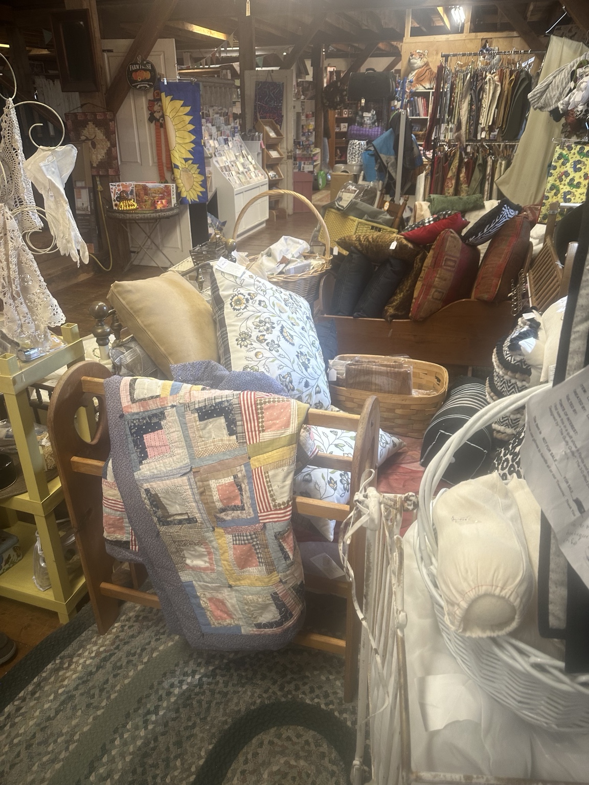 A patchwork quilt, patterned cushions and woven baskets among closely arranged displays inside the timber-framed shop.