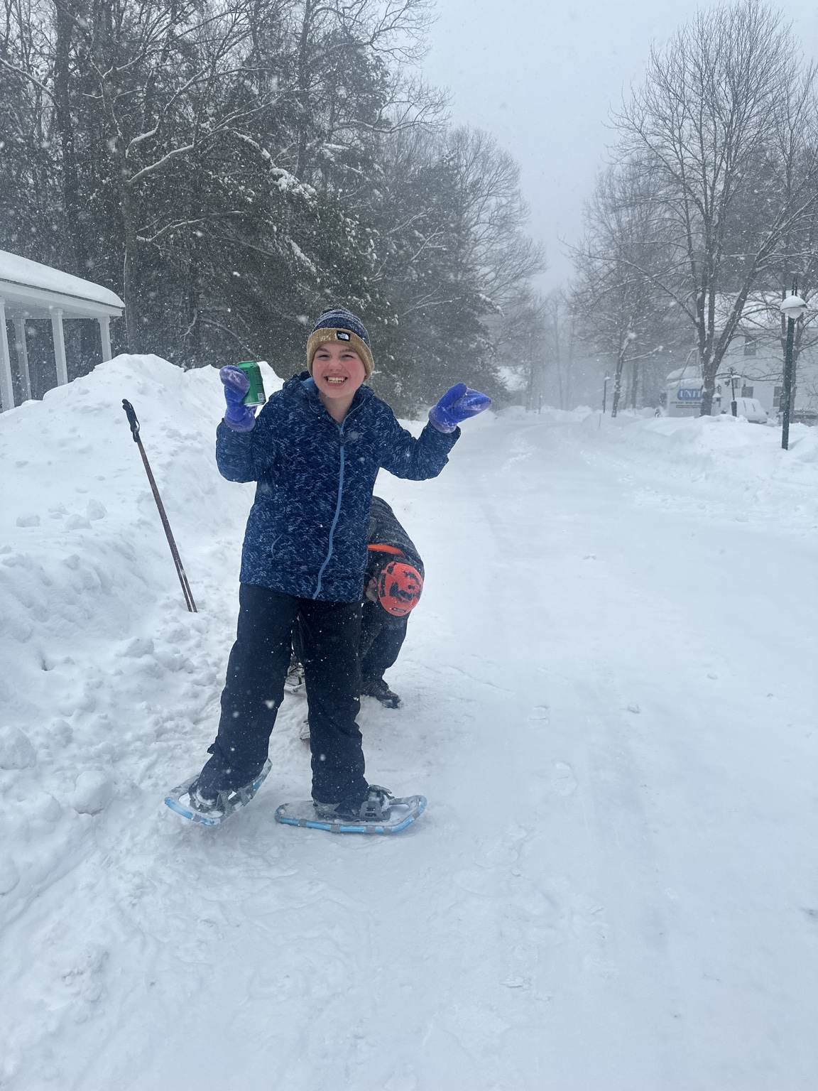 James grins at the camera in a navy jacket, knitted hat and purple mittens while Michael helps with his snowshoes.